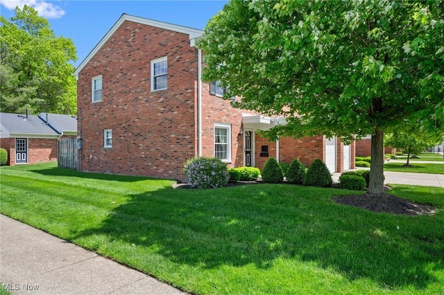 view of home's exterior with brick siding, a lawn, an attached garage, and driveway
