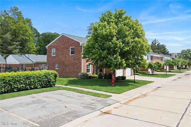 view of home's exterior featuring brick siding, a yard, uncovered parking, and a residential view