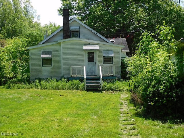 back of house with a yard and a chimney