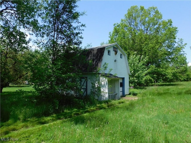 view of side of property with a gambrel roof, a barn, and an outdoor structure