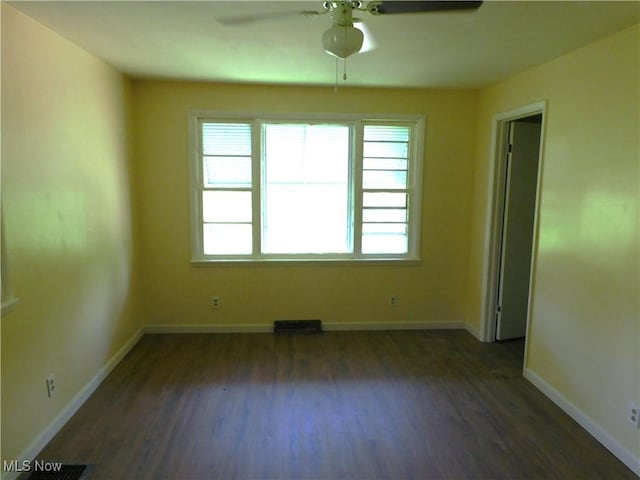 spare room featuring a ceiling fan, dark wood-type flooring, and baseboards