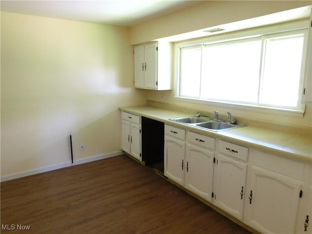 kitchen with a sink, dark wood-style flooring, white cabinetry, and baseboards