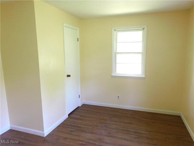 unfurnished room featuring dark wood-style floors and baseboards