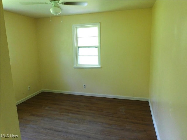 spare room with dark wood-style flooring, baseboards, and ceiling fan