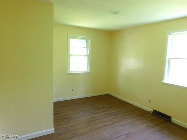 empty room featuring baseboards and dark wood-style floors