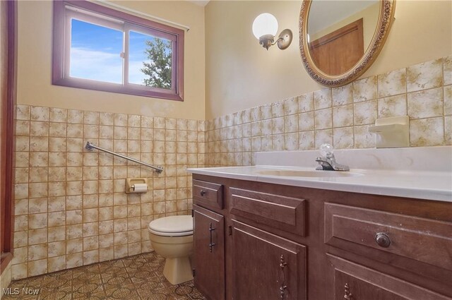12395 Carter Rd, Concord, OH 44077 - half bath featuring tile walls, toilet, vanity, tile patterned floors, and a wainscoted wall