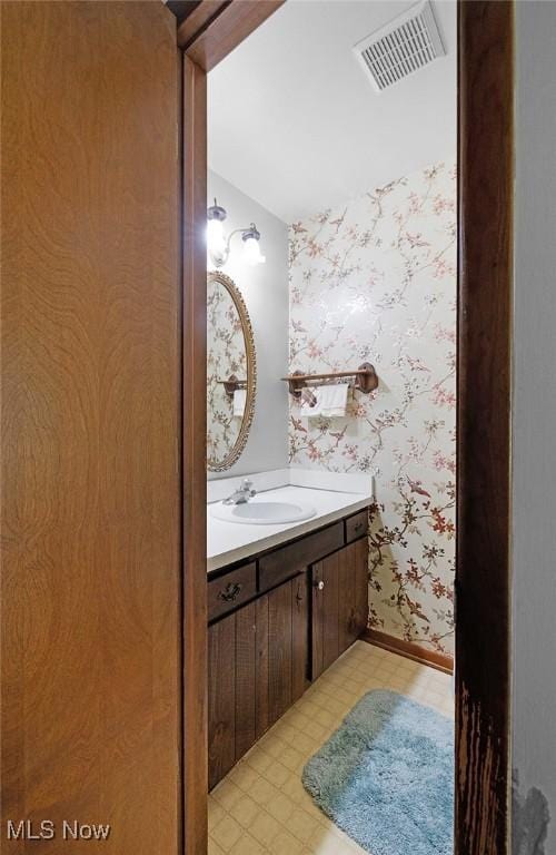bathroom featuring wallpapered walls, vanity, and lofted ceiling