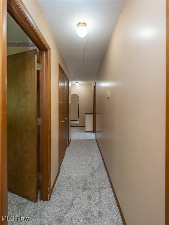 hall with light carpet and arched walkways