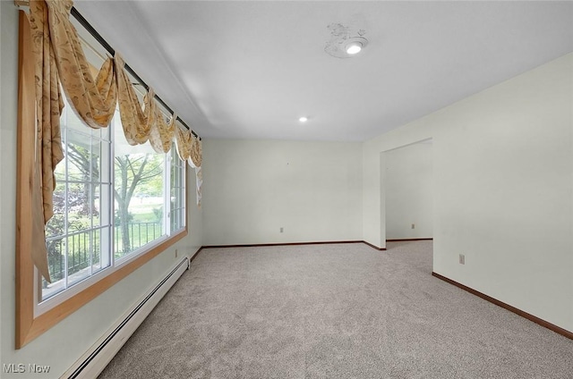 carpeted empty room featuring a baseboard heating unit and baseboards