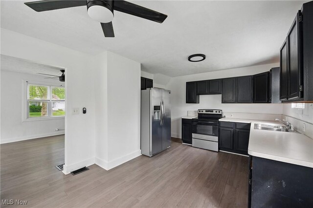 423 Kansas Ave, Lorain, OH 44052 - kitchen with stainless steel appliances, a sink, a ceiling fan, dark cabinets, and wood finished floors