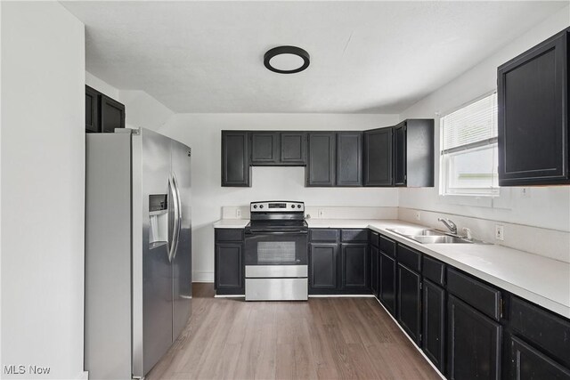 423 Kansas Ave, Lorain, OH 44052 - kitchen with stainless steel appliances, a sink, light wood-type flooring, light countertops, and dark cabinets