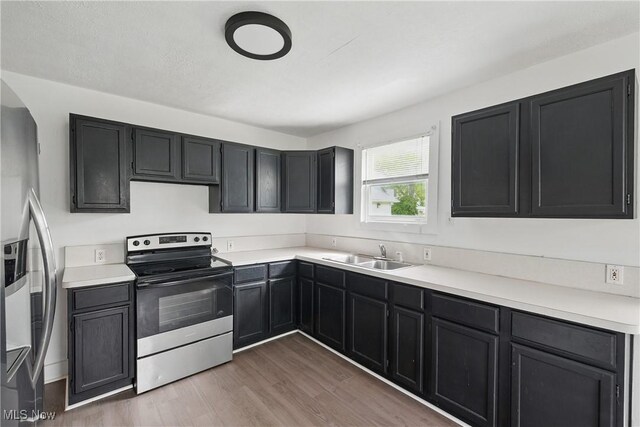 423 Kansas Ave, Lorain, OH 44052 - kitchen with stainless steel appliances, a sink, wood finished floors, light countertops, and dark cabinetry