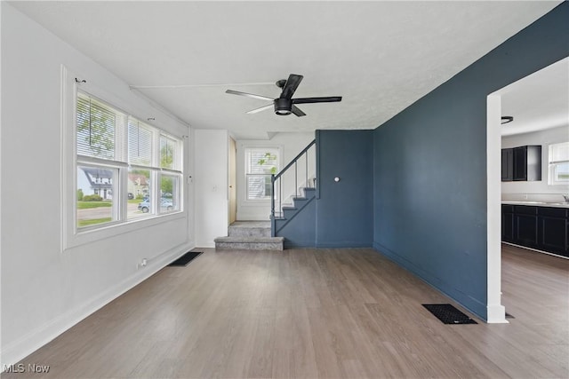 423 Kansas Ave, Lorain, OH 44052 - unfurnished living room featuring light wood finished floors, ceiling fan, baseboards, and stairway