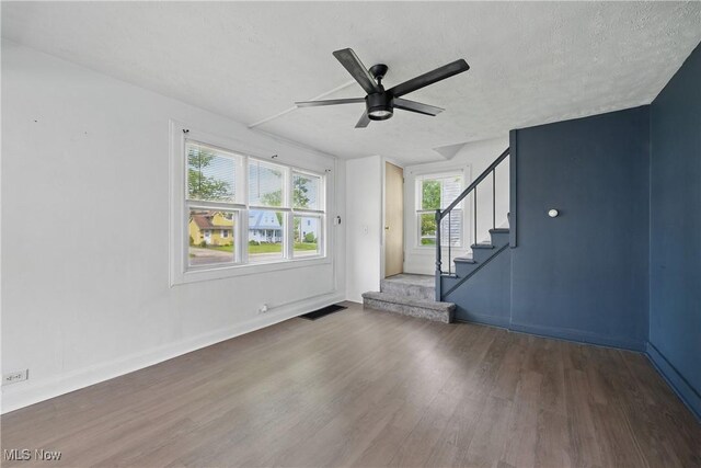 423 Kansas Ave, Lorain, OH 44052 - unfurnished living room with wood finished floors, a ceiling fan, stairs, a textured ceiling, and baseboards