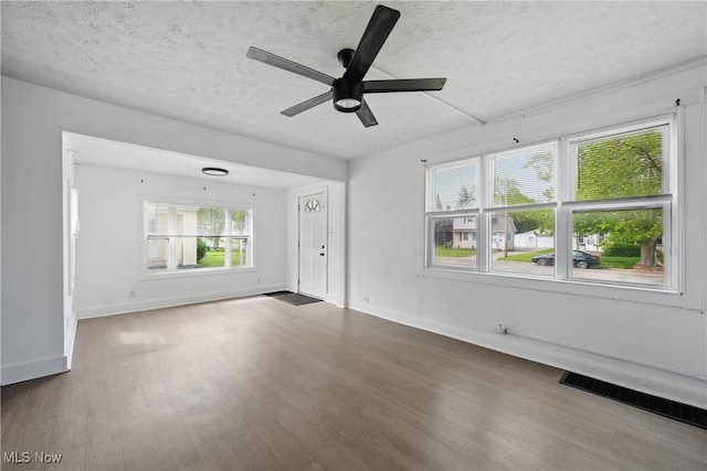 423 Kansas Ave, Lorain, OH 44052 - unfurnished living room with ceiling fan, a textured ceiling, wood finished floors, and baseboards