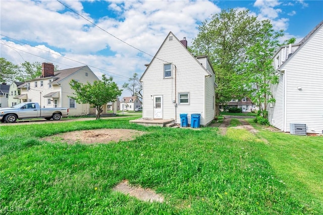 423 Kansas Ave, Lorain, OH 44052 - rear view of house with a chimney, a lawn, central air condition unit, and a residential view