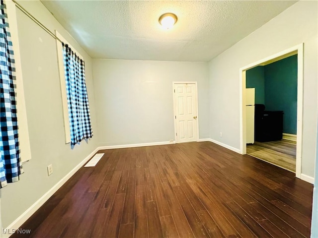 6815 Lawn Ave, Cleveland, OH 44102 - unfurnished room featuring dark wood-type flooring, a textured ceiling, and baseboards