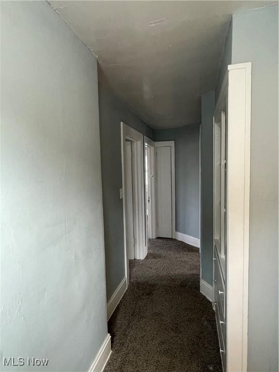 hallway featuring carpet flooring and baseboards