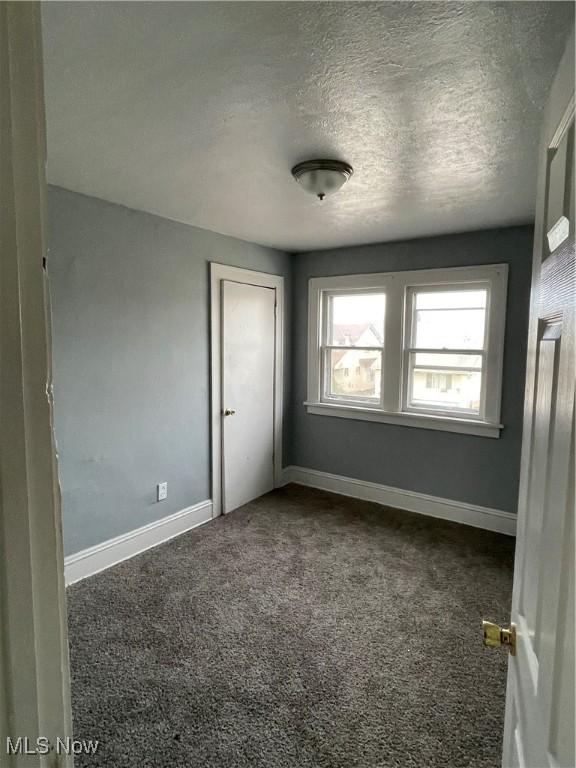 unfurnished bedroom featuring carpet flooring, baseboards, and a textured ceiling