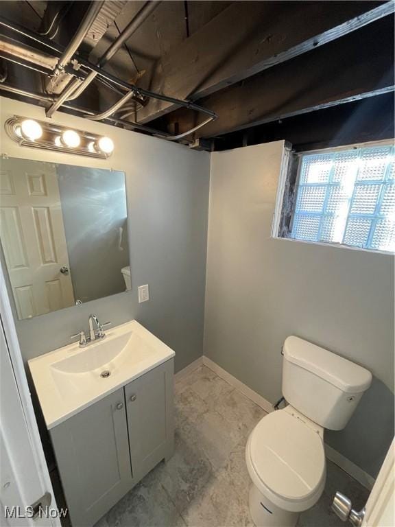 bathroom featuring toilet, vanity, baseboards, and marble finish flooring
