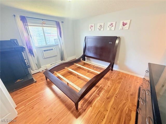 bedroom featuring light wood-type flooring and an AC wall unit