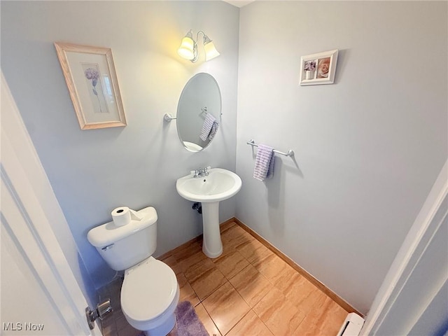 half bath featuring toilet and baseboards