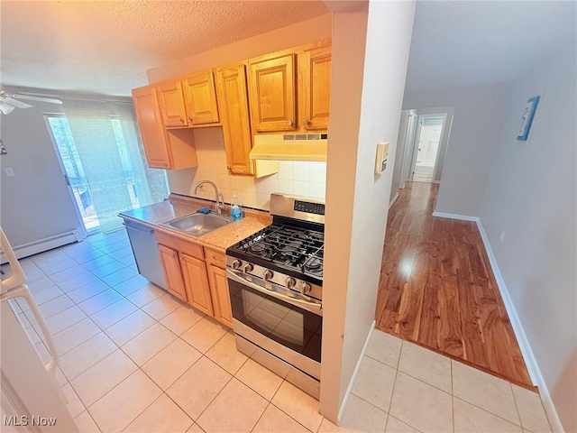 kitchen with stainless steel appliances, a sink, under cabinet range hood, a ceiling fan, and a baseboard heating unit