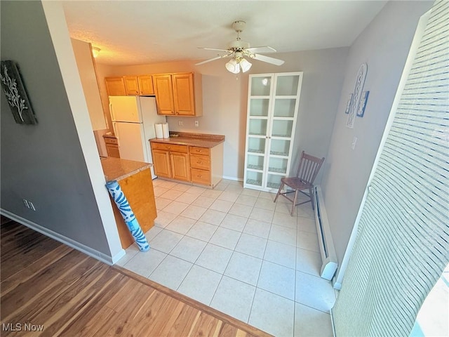 kitchen with freestanding refrigerator, light brown cabinets, ceiling fan, baseboards, and light countertops