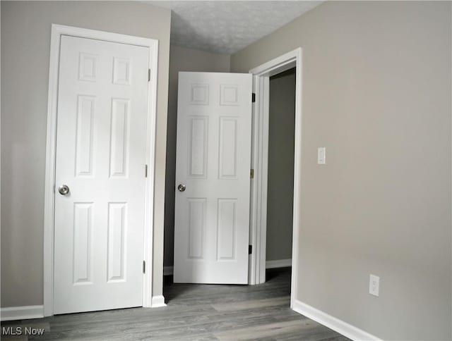 unfurnished bedroom with baseboards, wood finished floors, and a textured ceiling