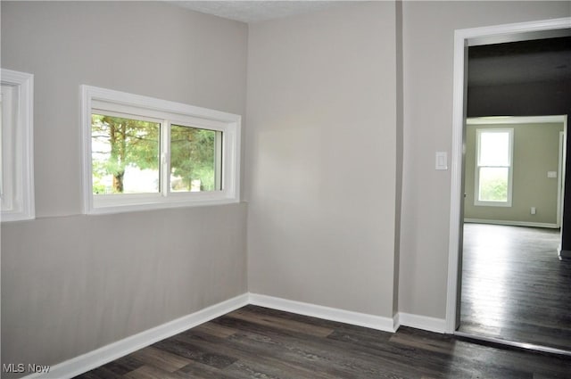empty room featuring dark wood finished floors and baseboards