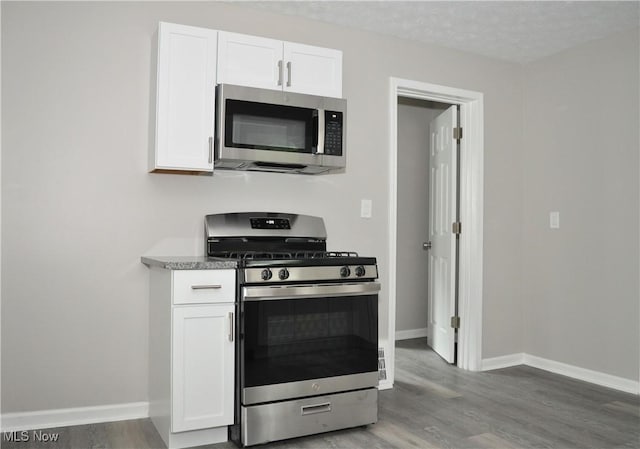 kitchen featuring appliances with stainless steel finishes, white cabinets, and wood finished floors
