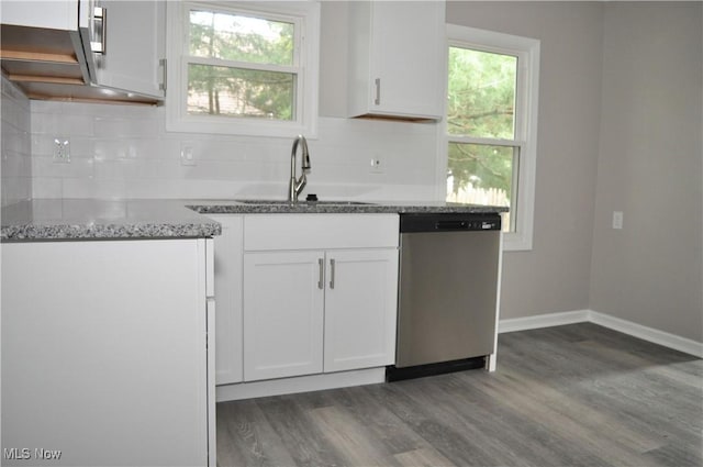 kitchen with dishwasher, a sink, dark wood-type flooring, stone countertops, and decorative backsplash