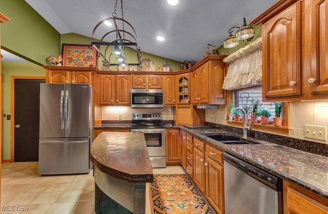 38 Choctaw Trl, Malvern, OH 44644 - kitchen featuring appliances with stainless steel finishes, lofted ceiling, dark stone counters, brown cabinetry, and backsplash