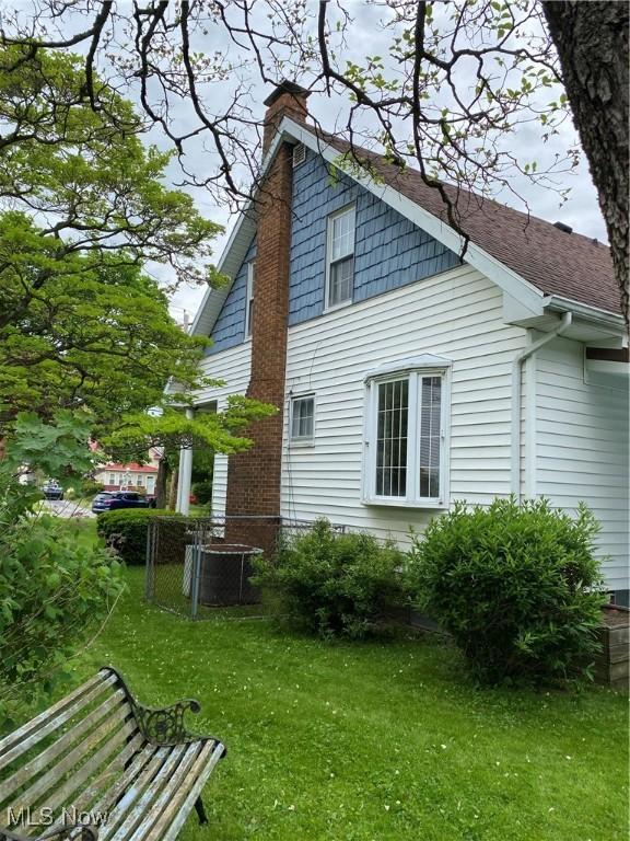 1912 Lisbon St, East Liverpool, OH 43920 - view of side of property featuring a chimney, a yard, and roof with shingles
