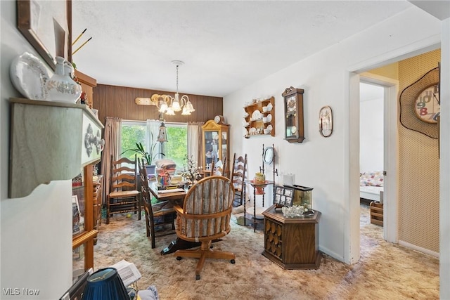 dining area with carpet, a chandelier, wood walls, and baseboards