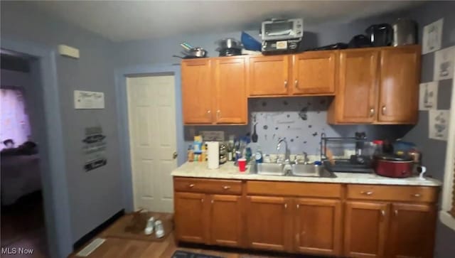 kitchen featuring a sink, light countertops, and brown cabinetry