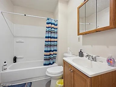 bathroom featuring toilet, shower / bath combination with curtain, and vanity
