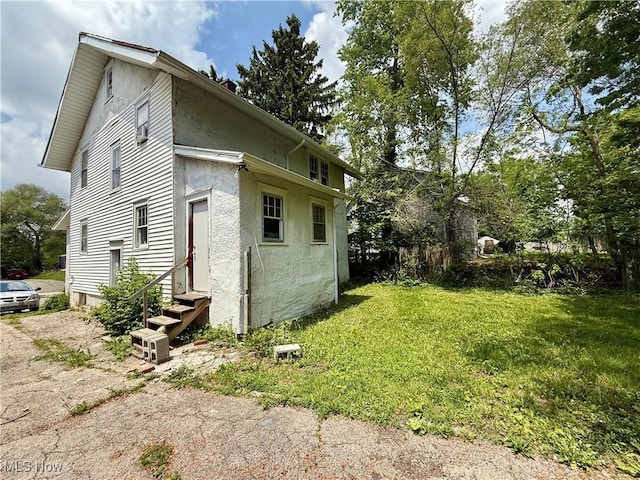 327 Garfield Ave, Lima, OH 45805 - view of side of home with entry steps, stucco siding, and a lawn