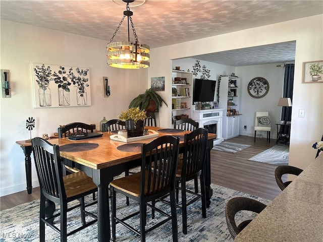 59010 Palmer St, Byesville, OH 43723 - dining space featuring wood finished floors, baseboards, a fireplace, and a textured ceiling