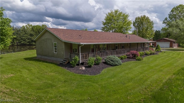 rear view of property with covered porch, a lawn, and a detached garage