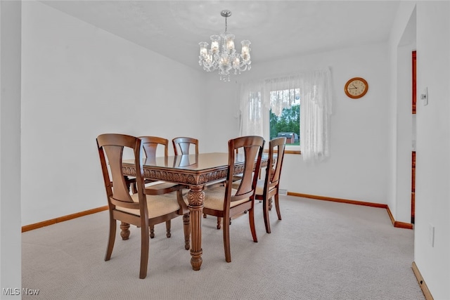dining space featuring a chandelier, light carpet, and baseboards