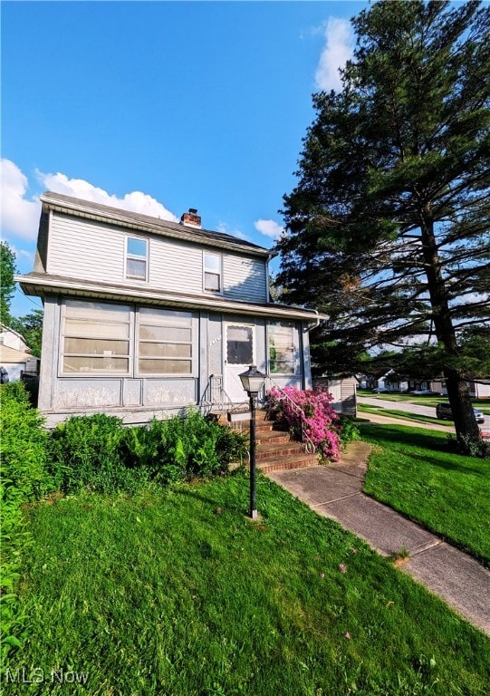 view of front of property featuring a chimney and a front yard