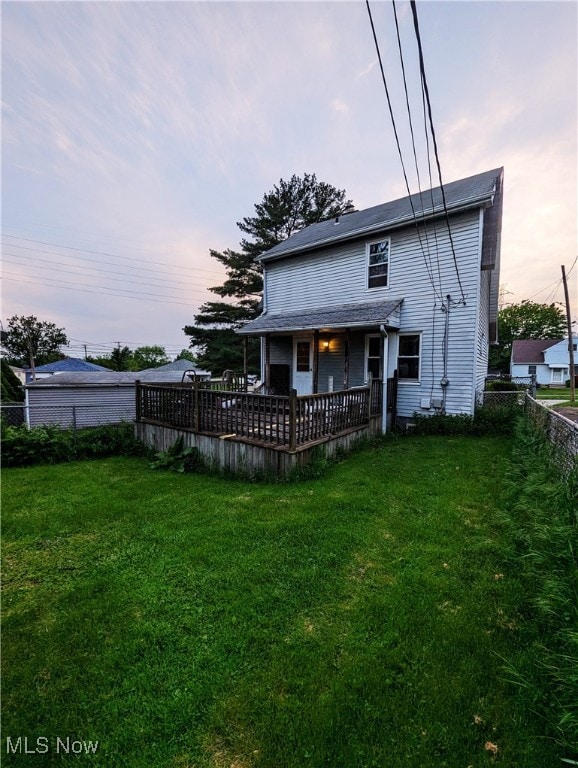 back of house at dusk featuring a deck
