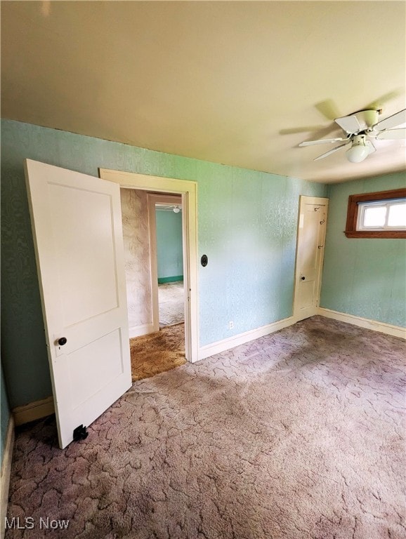 spare room with carpet, a ceiling fan, and baseboards