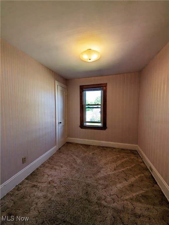 carpeted spare room featuring baseboards