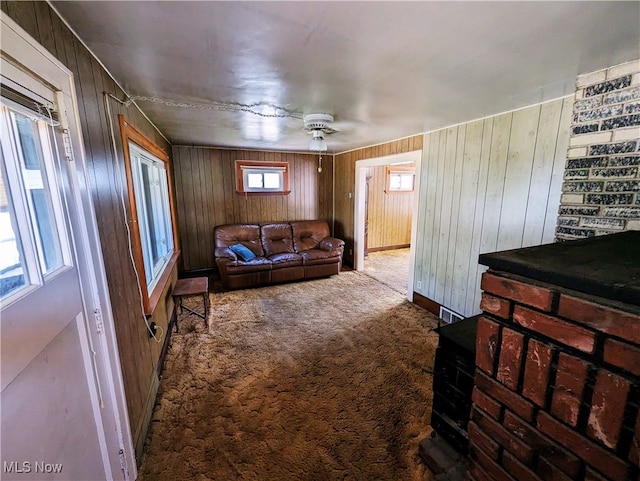 carpeted living room featuring a ceiling fan and wood walls