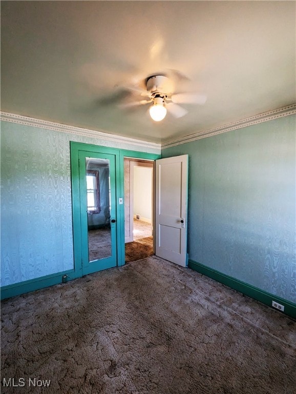 unfurnished bedroom featuring carpet floors, a ceiling fan, baseboards, and ornamental molding