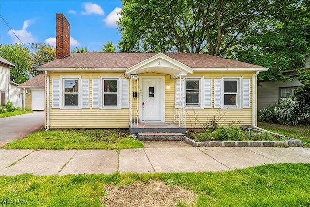 579 Main St, Conneaut, OH 44030 - bungalow with a chimney, a shingled roof, and a garage