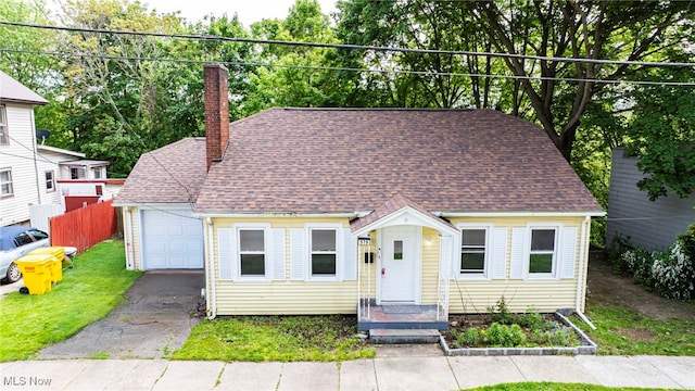 579 Main St, Conneaut, OH 44030 - view of front facade featuring a chimney, asphalt driveway, an attached garage, and a shingled roof