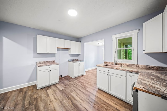 579 Main St, Conneaut, OH 44030 - kitchen featuring light wood-style floors, white cabinetry, baseboards, and a sink